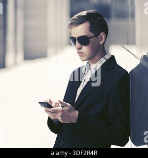 Junge gut aussehender Geschäftsmann mit Smart Phone in der Stadt. Stockfoto