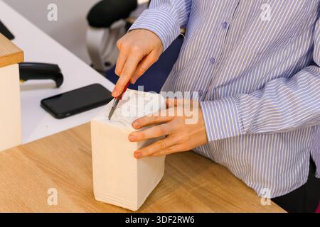 Arbeiter bereitet sich vor, den Inhalt des verpackten Pakets am Serviceschalter zu prüfen Stockfoto