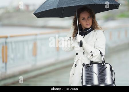 Nachdenkliche Frau mit Regenschirm im Regen Stockfoto