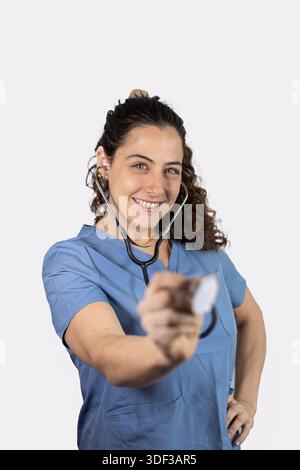 Ärztin mit Peelings und Stethoskop gegen die Kamera vor weißem Hintergrund Stockfoto