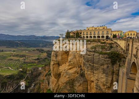Besucher bewundern atemberaubende Ausblicke von der Klippe in Ronda, Spanien, mit grünen Hügeln und Bergen, die die Szene umrahmen. Stockfoto