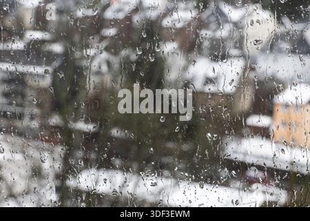 Der Regen flimmert von außen auf die Fensterscheibe Stockfoto