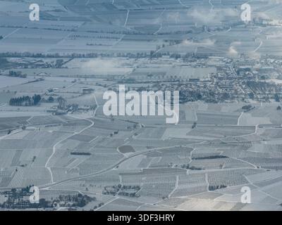 Aus der Vogelperspektive auf eine ruhige Winterlandschaft mit schneebedeckten Feldern und Dächern, die eine ruhige, monochromatische Szene schafft, Orschwiller, Grand Est, Frankreich Stockfoto