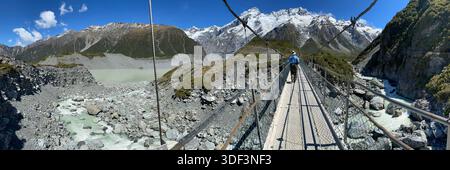 Ein Wanderer überquert die dritte Brücke auf dem Hooker Valley Trail im neuseeländischen Mt. Cook/Aoraki Nationalpark. Foto von Marilynn Mastroianni. Stockfoto