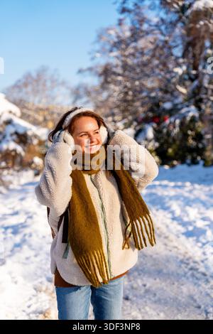 Lächelnde junge Frau in warmen Kleidern draußen an einem kalten Wintertag im Stadtpark. Stockfoto