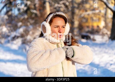 Eine junge Frau, die Ohrenschützer trägt, steht draußen an einem kalten Wintertag Stockfoto