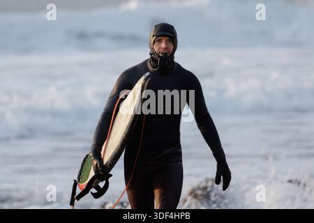 Surfermann mit Surfbrett im Winter-Neoprenanzug Stockfoto