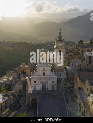 Blick aus der Vogelperspektive auf die Chiesa Madre di San Giorgio Martyre, majestätisch vor der Kulisse der sanften Berge, die im goldenen Licht getaucht sind, CAC Stockfoto