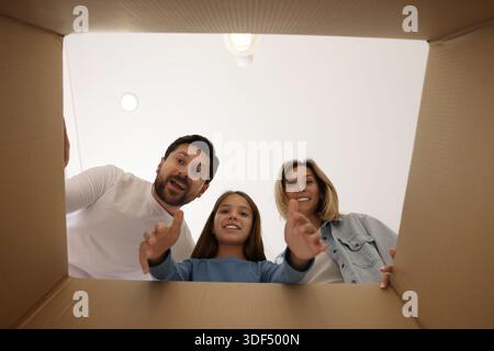 Begeisterte Familie, die in Kartons im Innenbereich schaut, Blick aus dem Inneren des Pakets Stockfoto