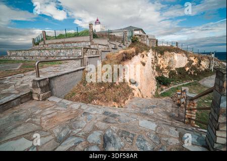 Der Leuchtturm von Tapia de Casariego steht auf einer zerklüfteten Klippe mit Steintreppen, die zum Meer führen und die dramatische Küste von Asturi zeigen Stockfoto