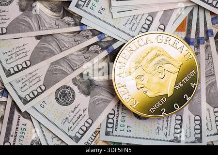 KIEW, UKRAINE - 13. DEZEMBER 2025 Trump Goldmünze auf großen Mengen von US-Dollar-Banknoten Stockfoto