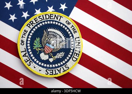KIEW, UKRAINE - 13. DEZEMBER 2025 Aufkleber mit dem Siegel des Präsidenten der Vereinigten Staaten auf der Flagge der Vereinigten Staaten von Amerika mit Sternen und Streifen in Nahaufnahme Stockfoto