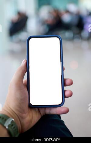 Männliche Hand, die Smartphone mit leerem Bildschirm am Flughafen hält Stockfoto