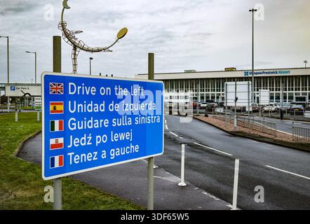 A Melden Sie sich in mehreren Sprachen an und erinnern Sie den Fahrer an das Fahren auf der linken Seite. Außenansicht des Glasgow Prestwick Airport, Ayrshire, Schottland, Großbritannien Stockfoto