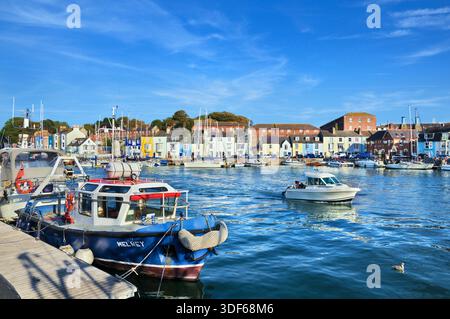 Blick über das Wasser von Weymouth Old Harbour im Sommer auf Boote und farbenfrohe Reihenhäuser auf der Nothe Parade, Weymouth, Dorset, England, Großbritannien Stockfoto