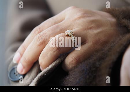 Goldener Ring mit Diamanten an der Hand in Winterkleidung Stockfoto