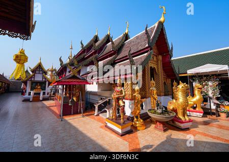 Traditionelle Lanna-Architektur und heilige Statuen im Wat Phra That Doi Kham Tempel auf der Bergseite von Chiang Mai, Nordthailand Stockfoto