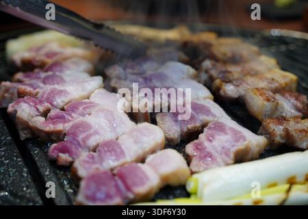 Brutzelnder koreanischer Schweinebauch (Samgyeopsal) auf einer heißen Grillplatte Stockfoto