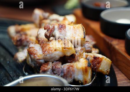 Brutzelnder koreanischer Schweinebauch (Samgyeopsal) Grillen auf einem heißen Grill, Nahaufnahme. Stockfoto