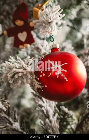 Weihnachtsbaum mit roten Ornamenten und Details wie kleinen roten Kugeln und Marionetten, die an der Kiefer hängen Stockfoto