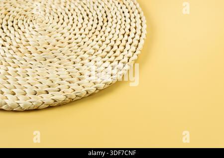 Draufsicht der braunen Korbplatte auf gelbem Hintergrund. Rundes Strohfach, flache Ladefläche, Kopierraum. Stockfoto