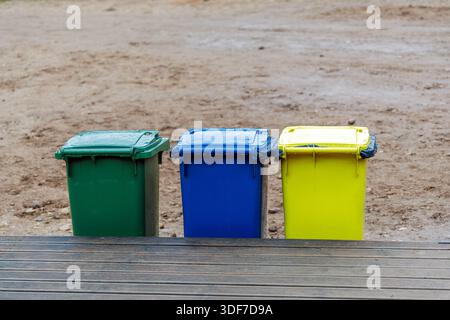 Drei Kunststoffabfallbehälter in verschiedenen Farben zur Mülltrennung zur Unterstützung des Recyclings und des Umweltschutzes in öffentlichen Räumen. Stockfoto