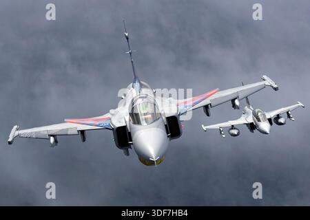 Eine tschechische Luftwaffe JAS 39C Gripen fliegt an den NATO-Tagen 2025 zusammen mit einer JAS 39D Gripen in einer koordinierten Luft-Luft-Formation. Beide Flugzeuge tragen eine Gedenklackierung zur Feier des 20-jährigen Betriebs von Gripen im tschechischen Dienst. Die von Saab entworfenen Mehrzweckjäger verfügen über Dreiecksflügel mit Canards und werden von Volvo Aero RM12 Turbofan-Motoren angetrieben. Die Szene dokumentiert stabile Formationsflüge, sichtbare nationale Insignien und standardmäßige externe Konfiguration, die für die operative Ausbildung und die öffentliche Flugschau innerhalb eines NATO-Rahmens verwendet wird. Stockfoto