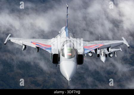 Zwei Saab JAS 39 Gripen-Kampfflugzeuge der Tschechischen Luftwaffe halten während einer Luft-Luft-Ausstellung an den NATO-Tagen 2025 Formationsflug. Das Bild zeigt eine einsitzige JAS 39C-Variante und eine zweisitzige JAS 39D-Variante, die beide in einer Gedenklackierung für 20 Jahre Service tragen. Der Gripen ist ein Überschall-Multifunktionsjet mit Delta-Flügel, Canards und einem Volvo Aero RM12 Turbofan-Motor. Sichtbare Elemente sind nationale Markierungen, Standard-Flugkonfiguration und diszipliniertes Formationsfliegen. Stockfoto