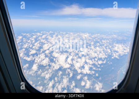 Wunderschöner Blick auf den bewölkten blauen Himmel mit Wolken aus dem Fenster des Flugzeugfensters über dem Himmel. Stockfoto