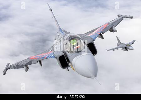 Luft-Luft-Foto von zwei tschechischen Luftwaffe Saab JAS 39C Gripen, die an den NATO-Tagen 2025 in enger Formation fliegen. Die Flugzeuge sind 9234 und 9240 mit den Seriennummern 39234 und 39240 registriert und weisen eine 20-jährige Dienstzeit-Lackierung auf. Das Bild enthält Nahaufnahmen der Piloten während des Formationsfluges im Cockpit. Die JAS 39C ist ein einsitziger Mehrzweckjäger mit Delta-Flügeln, Canards und einem Volvo RM12 Turbofan-Motor. Stockfoto