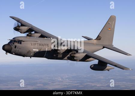 Nahaufnahme Luft-Luft-Foto der Luftwaffe KC-130J Hercules, Registrierung 5505, Seriennummer 382-5971, NATO-Tage 2025. Das Bild zeigt Cockpitfenster, Besatzung im Inneren, vier Allison AE 2100D3 Turboprop-Motoren mit Sechsflügelpropellern, Hochflügelrumpfbau, verlängertes Fahrwerk und Tankkapseln. Die Flugzeuge führen taktische Luftbrücke, Luftbetankung und Personentransporte durch und demonstrieren die Einsatzfähigkeit der deutschen Luftwaffe. Stockfoto
