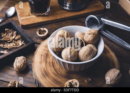 Walnüsse in Schüssel und Nussknacker auf rustikalem Tisch Stockfoto