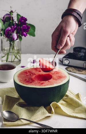 Der Löffel mit Stück Wassermelone in man Hand Stockfoto
