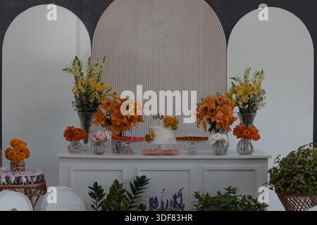 Blumendekorationen und Leckereien auf dem Präsentationstisch Stockfoto