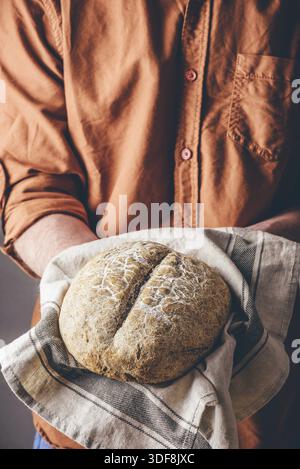Mann hält ein Laib von frisch gebackenem Roggenbrot Stockfoto