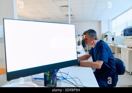 Ein fokussierter Wissenschaftler analysiert Proben mit einem Mikroskop in einem sauberen und organisierten Labor. Helles Licht aus den Fenstern verbessert den Arbeitsbereich und präsentiert fortschrittliche Geräte. || Modell freigegeben Stockfoto