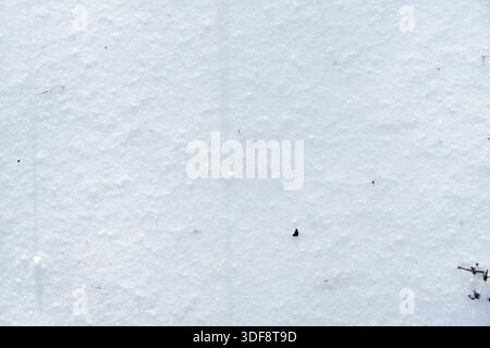 Hochwinkelansicht eines strukturierten weißen Schneehintergrunds mit winzigen organischen Flecken. Ideal für minimalistische Designs oder Overlays mit Naturmotiven Stockfoto