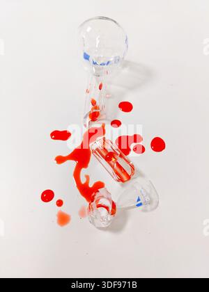 Eine gebrochene Ampulle und verschüttete Flüssigkeit erzeugen ein auffälliges Bild von Zerbrechlichkeit und potenzieller Gefahr Stockfoto