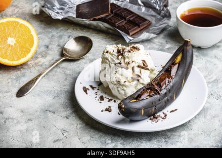 Süßes Dessert. Gegrillte Banane mit dunkler Schokolade, Zitrussaft und Vanilleeis Stockfoto