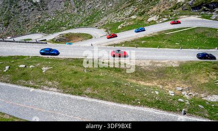Aus der Vogelperspektive farbenfrohe Sportwagen auf einer gewundenen Bergstraße. Stockfoto