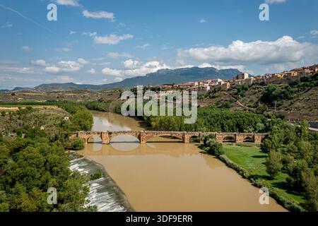 Malerischer Fluss mit historischer Steinbrücke über grüne Ufer in der Nähe Einer Bergstadt, San Vicente de la Sonsierra, Spanien Stockfoto