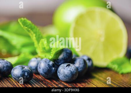 Frische Heidelbeeren und die Hälfte Limette und Minzblätter im Hintergrund. Zutaten für die Zubereitung von Reinigungswasser Stockfoto