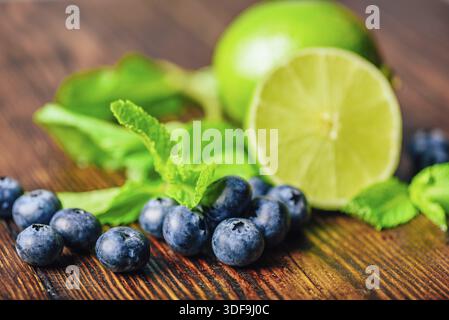 Frische Heidelbeeren, die Hälfte Limette und Minzblätter. Zutaten für die Zubereitung von aromatisiertem Wasser Stockfoto