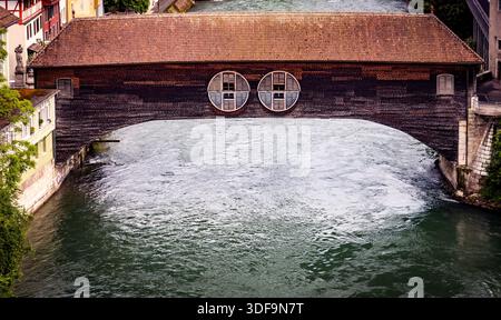 Historische Holzbrücke über einen Fluss mit kreisrunden Fenstern. Stockfoto