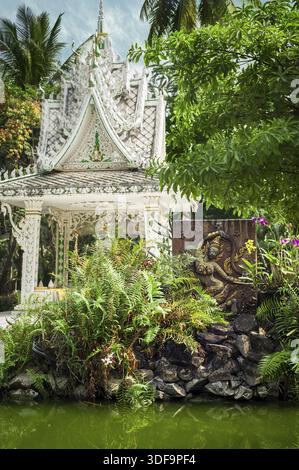 Buddhistische Schnitzerei und Pagode im Freiluftpark mit dekorativen Pflanzen, die sich im Teich spiegeln. Religiöse Architektur der asiatischen Stadt an einem öffentlichen Platz. Vientiane, L. Stockfoto