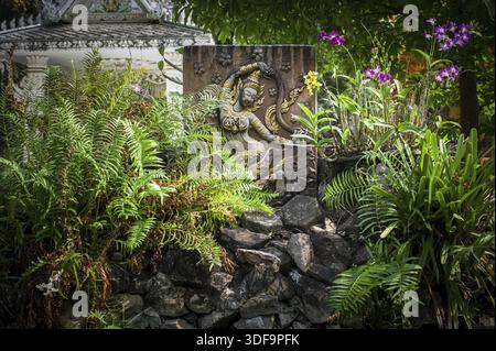Buddhistische Schnitzerei und Pagode im Freiluftpark mit dekorativen Pflanzen, die sich im Teich spiegeln. Religiöse Architektur der asiatischen Stadt an einem öffentlichen Platz. Vientiane, L. Stockfoto