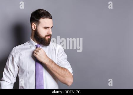 Gutaussehender bärtiger Geschäftsmann, der seine Krawatte anpasst Stockfoto