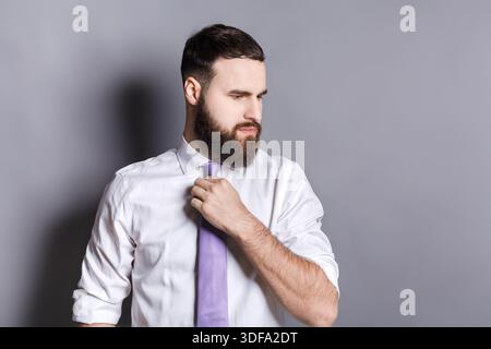 Gutaussehender bärtiger Geschäftsmann, der seine Krawatte anpasst Stockfoto