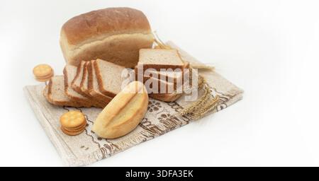 Geschnittenes Weizenbrot mit Brotscheiben und Getreideohren auf weißem Hintergrund Stockfoto