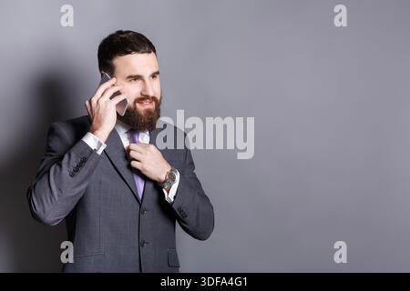 Fröhlicher bärtiger Geschäftsmann, der am Telefon spricht Stockfoto